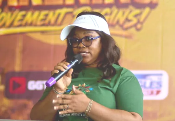 A speaker addressing the room at The Awakening, GGTV and Eagles FM banners behind her